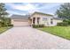 Brick driveway leading to a tan house with garage at 27325 Mistflower Dr, Wesley Chapel, FL 33544
