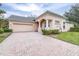 Brick driveway leading to a tan house with garage at 27325 Mistflower Dr, Wesley Chapel, FL 33544