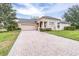 Brick driveway leading to a tan house with garage at 27325 Mistflower Dr, Wesley Chapel, FL 33544