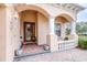 Inviting front porch with brick flooring, arched entryway, and decorative columns at 27325 Mistflower Dr, Wesley Chapel, FL 33544