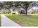 Single-story house with a screened porch and large oak tree in the yard at 27325 Mistflower Dr, Wesley Chapel, FL 33544