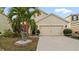 Front yard view of charming house with palm trees and two-car garage at 12017 Gillingham Harbor Ln, Gibsonton, FL 33534