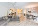 This open-concept living room features wood-look flooring, a gray sectional, and access to the kitchen at 23635 Oakside Blvd, Lutz, FL 33559