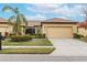 Front view of a tan, single-story house with a two-car garage and landscaping at 417 Brandywine Falls Ct, Apollo Beach, FL 33572