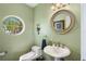 Elegant powder room featuring a pedestal sink and round mirror at 608 Columbus Dr, Tierra Verde, FL 33715