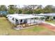White mobile home with carport, and a red driveway. Surrounding homes are visible at 37318 Lois Ave, Zephyrhills, FL 33542