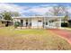 White single-wide mobile home with carport, landscaped lawn, and red driveway at 37318 Lois Ave, Zephyrhills, FL 33542