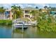 Waterfront property with a boat lift, grassy lawn, and a spiral staircase leading to the balcony at 808 Symphony Isles Blvd, Apollo Beach, FL 33572