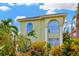 Front exterior featuring arched windows, bright green foliage, and lovely tropical accents at 808 Symphony Isles Blvd, Apollo Beach, FL 33572