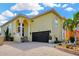 Two-story yellow home featuring a brick driveway, arched entryway and a black two car garage door at 808 Symphony Isles Blvd, Apollo Beach, FL 33572
