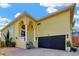Two-story yellow home featuring an arched entryway and a black two car garage door at 808 Symphony Isles Blvd, Apollo Beach, FL 33572
