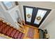 Inviting foyer with decorative glass double doors, hardwood floors and red runner on the staircase at 808 Symphony Isles Blvd, Apollo Beach, FL 33572