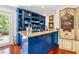 A blue wet bar area with wine rack, marble countertops, shelving and refined art accents at 1124 Seville Ne Ln, St Petersburg, FL 33704