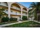 Condo building with exterior arches, neutral paint, well maintained landscape, and palm trees at 2258 World Parkway W Blvd # 8, Clearwater, FL 33763