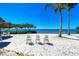 Scenic beachfront view with three chairs and clear water at 380 Aruba Cir # 203, Bradenton, FL 34209