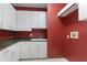 Laundry room with white cabinets, granite countertops, and a red accent wall at 843 Harbor Is, Clearwater Beach, FL 33767