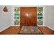 View of entryway with hardwood floors and double doors flanked by stained glass at 1302 Belcher Dr, Tarpon Springs, FL 34689