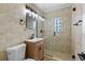 Updated bathroom with beige tile, glass shower, and wood vanity at 210 W Floriland Ave, Tampa, FL 33612