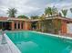 Inviting swimming pool surrounded by tropical plants and a pink house at 263 Overbrook E St, Largo, FL 33770