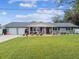 Gray brick ranch house with a spacious lawn, two-car garage, and covered porch at 3400 Lake Padgett Dr, Land O Lakes, FL 34639