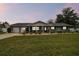 Gray brick ranch house with a spacious lawn, two-car garage, and covered porch at dusk at 3400 Lake Padgett Dr, Land O Lakes, FL 34639