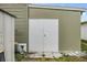 White storage shed with double doors, adjacent to a mobile home at 5322 Comanche St, Zephyrhills, FL 33542