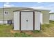 Grey metal storage shed with double doors in backyard at 5322 Comanche St, Zephyrhills, FL 33542