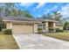 Tan house with a two-car garage and nicely landscaped lawn at 599 Centerwood Dr, Tarpon Springs, FL 34688