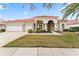 Tan house with tile roof, three-car garage, and landscaped yard at 9144 Highland Ridge Way, Tampa, FL 33647