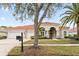 Tan house with tile roof, three-car garage, and landscaped yard at 9144 Highland Ridge Way, Tampa, FL 33647