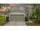 Two-story house with beige exterior, two-car garage, and landscaped yard at 10525 Lucaya Dr, Tampa, FL 33647