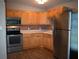 L-shaped kitchen with wood cabinets, stainless steel appliances, and tile backsplash at 11798 104Th St, Largo, FL 33773