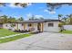 Modern home with light-colored walls, wood-toned columns, and a landscaped front yard at 1400 Farragut Dr, St Petersburg, FL 33710