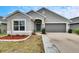 Gray house with two-car garage, stone walkway, and landscaping at 14525 Scottburgh Glen Dr, Wimauma, FL 33598