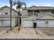 Tan two-story townhouses with attached garages and a shared driveway at 1946 Hammocks Ave, Lutz, FL 33549