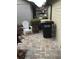 Back patio with brick pavers, trash cans, and a white adirondack chair at 2217 Sequoia Dr, Clearwater, FL 33763