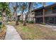 Ground level view of condo building with walkway, trees, and patio at 2670 Sequoia Ter # 1406, Palm Harbor, FL 34683