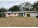 Ranch style home with pink exterior, mature landscaping, and a two-car garage at 3230 San Bernadino St, Clearwater, FL 33759