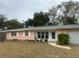 Ranch-style home with pink exterior, grey roof, and landscaped lawn at 3230 San Bernadino St, Clearwater, FL 33759