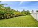 Large grassy backyard with a white vinyl fence and tropical landscaping at 3795 Morgons Castle Ct, Land O Lakes, FL 34638