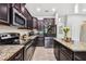 Modern kitchen with dark wood cabinets, granite countertops, and stainless steel appliances at 3795 Morgons Castle Ct, Land O Lakes, FL 34638