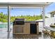 Outdoor kitchen with grill, mini-fridge, and pool view at 3795 Morgons Castle Ct, Land O Lakes, FL 34638