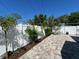 Private backyard oasis with paver patio, lush landscaping, and white vinyl fence at 410 W Lemon St, Tarpon Springs, FL 34689