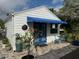 White cottage with blue awning, small patio, and potted plants at 410 W Lemon St, Tarpon Springs, FL 34689