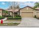 Tan two-car garage villa with a landscaped front yard at 430 Cedar Falls Dr, Apollo Beach, FL 33572