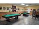 Well-lit game room with two billiard tables, comfortable seating, and bookshelves at 4361 Tahitian Gardens Cir # C, Holiday, FL 34691