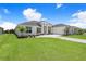 A view of the home's front exterior featuring manicured lawns and a driveway to the four-car garage at 5112 Lake Toscana Dr, Wimauma, FL 33598