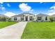 Charming single-story home featuring a lush green lawn and a long driveway leading to the front entrance at 5112 Lake Toscana Dr, Wimauma, FL 33598