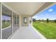 Covered back patio looking out onto a spacious lawn with pond view and blue skies at 5214 Lake Venice Dr, Wimauma, FL 33598