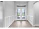 Light-filled foyer featuring wood floors, stylish wainscoting, and an elegant glass-paneled front door at 5214 Lake Venice Dr, Wimauma, FL 33598